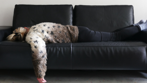 a person exhausted on a black leather sofa