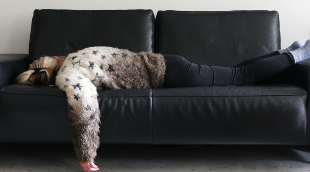 a person exhausted on a black leather sofa