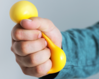 a person, probably a stress actor, holding and squeezing a stress ball