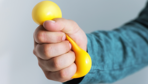 a person, probably a stress actor, holding and squeezing a stress ball