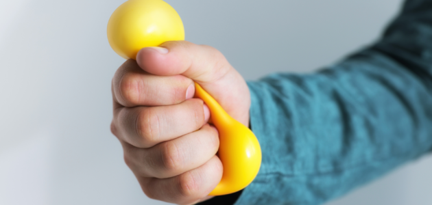 a person, probably a stress actor, holding and squeezing a stress ball