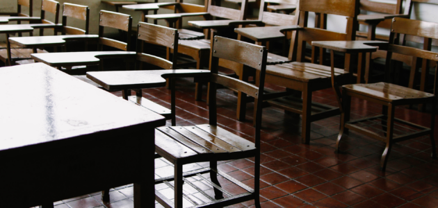 an empty classroom, made up of antique, wooden desk/chairs