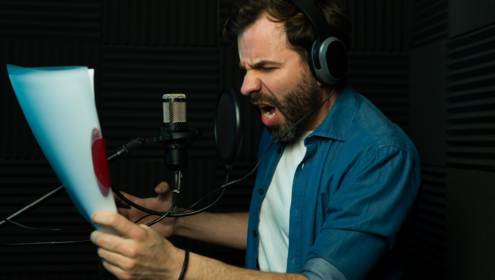 An actor holding a script speaking into a microphone